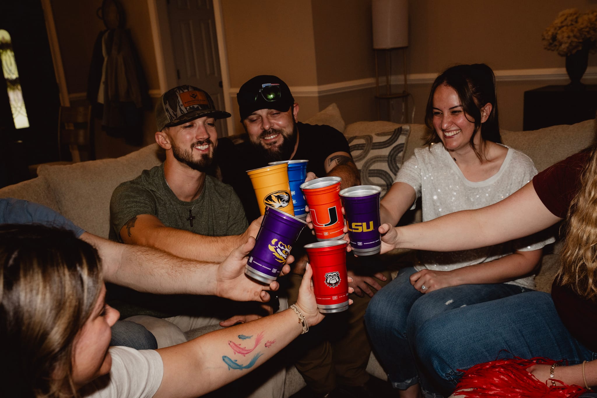Friends toasting officially licensed college Top Cup aluminum cups at a game day watch party